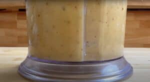 Close-up of a creamy smoothie blend in a blender jar on a wooden countertop.